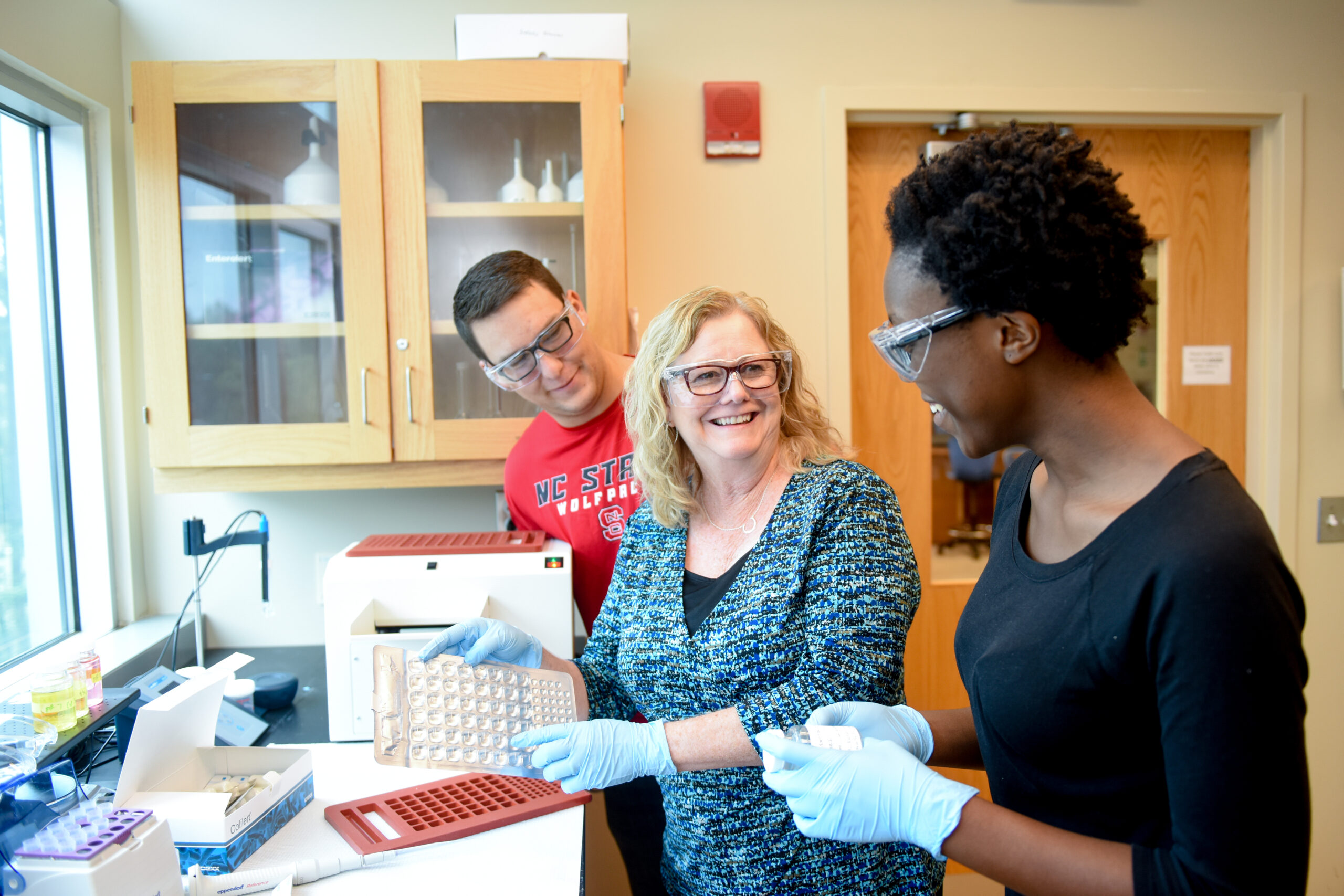 Three researchers in a lab examining their results