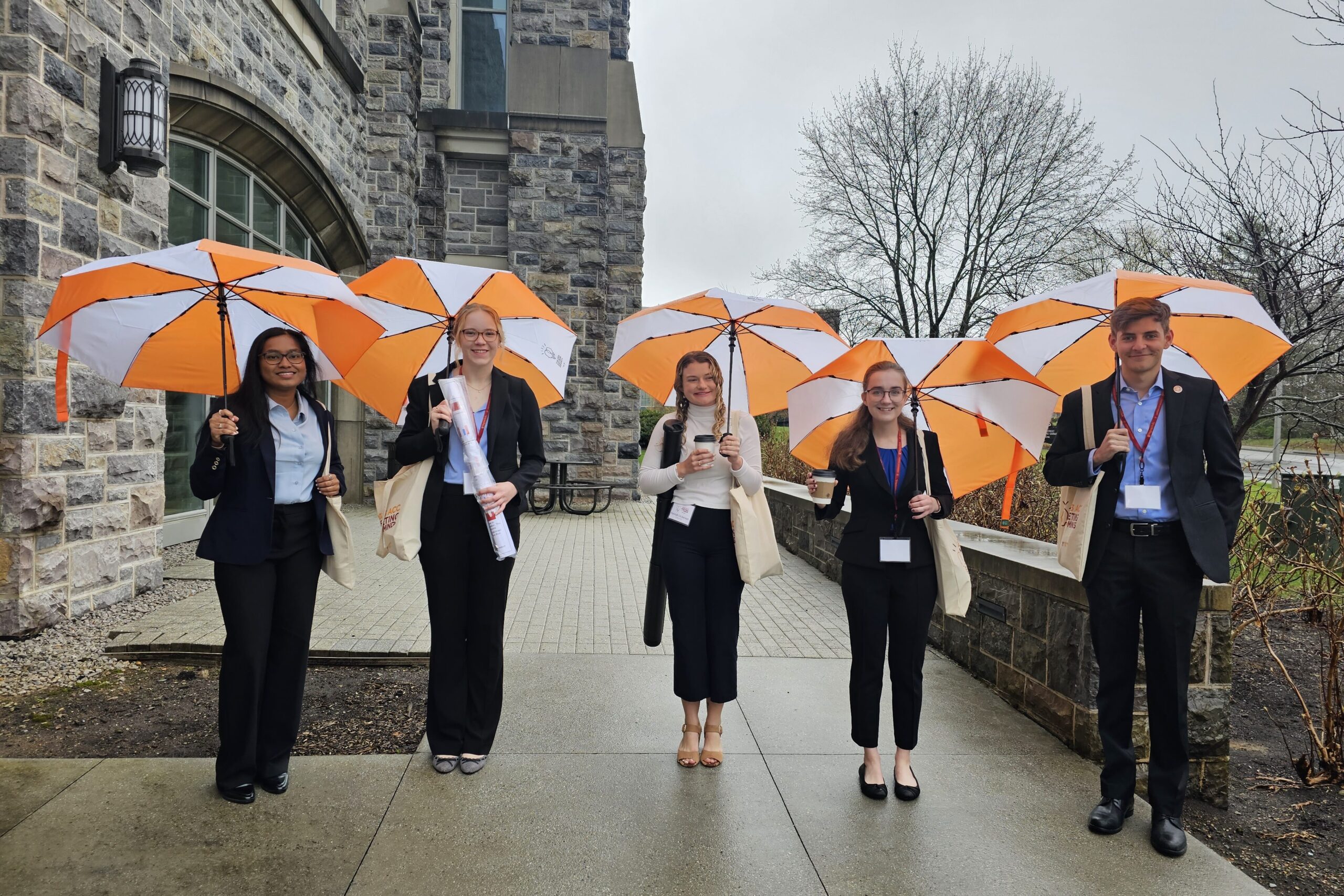 Student presentrs at ACC MotM VA, standing outside with umbrellas.